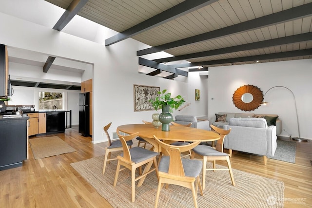 dining area featuring beam ceiling, light wood-type flooring, and baseboards