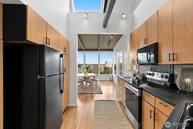 kitchen featuring tasteful backsplash, dark countertops, beam ceiling, light wood-style floors, and black appliances