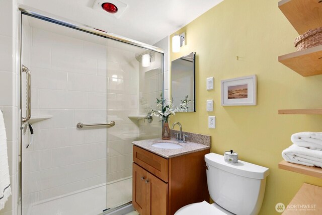 bathroom featuring toilet, a stall shower, and vanity