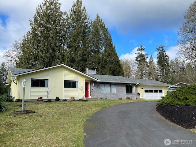 single story home featuring brick siding, a chimney, a front yard, a garage, and driveway