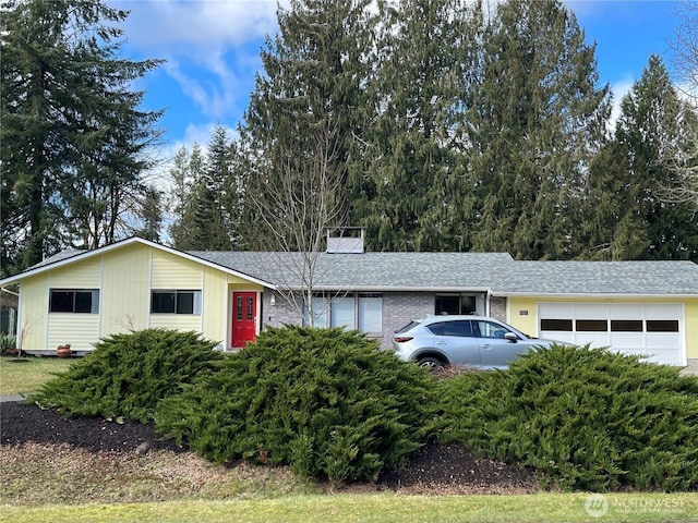 ranch-style home with a garage, roof with shingles, brick siding, and a chimney