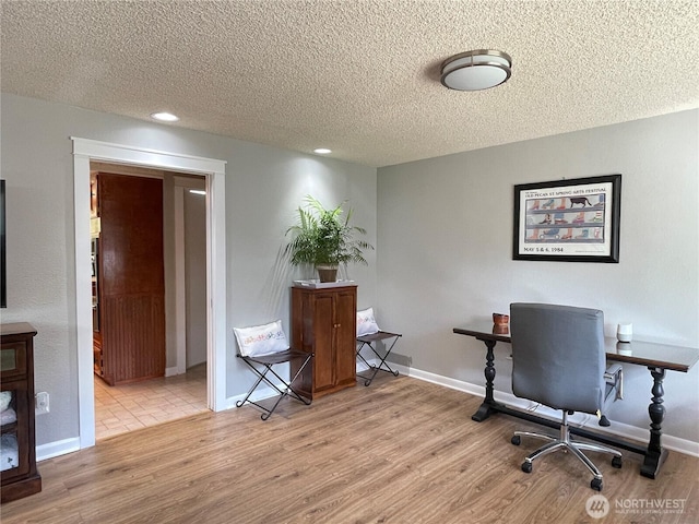 office area with a textured ceiling, baseboards, and wood finished floors