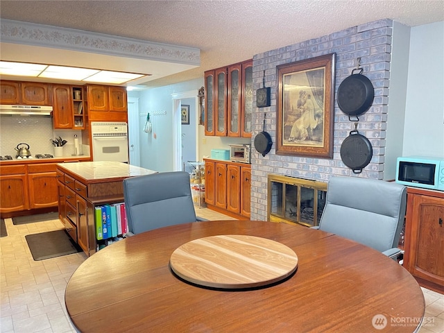 dining room featuring a textured ceiling, a brick fireplace, and a toaster