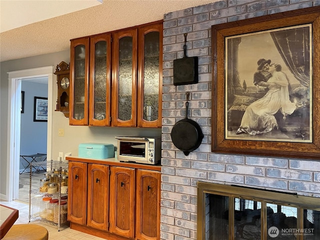 kitchen with glass insert cabinets, brown cabinets, a toaster, and a textured ceiling