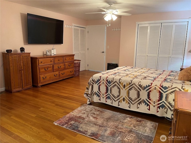 bedroom featuring multiple closets, a ceiling fan, and wood finished floors