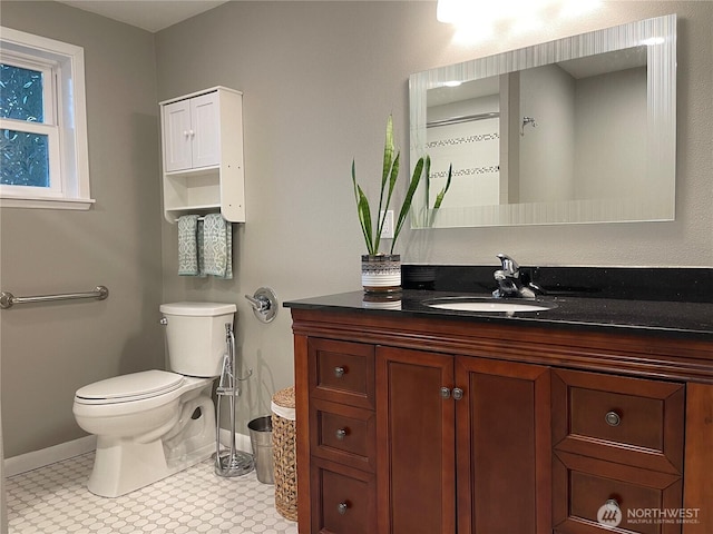 bathroom featuring toilet, baseboards, and vanity