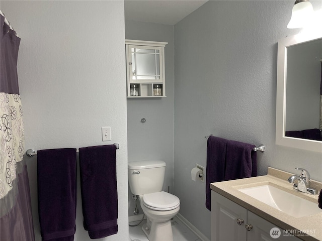 bathroom with vanity, toilet, and baseboards