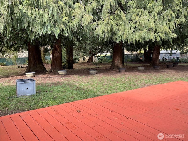 wooden terrace featuring a yard and fence