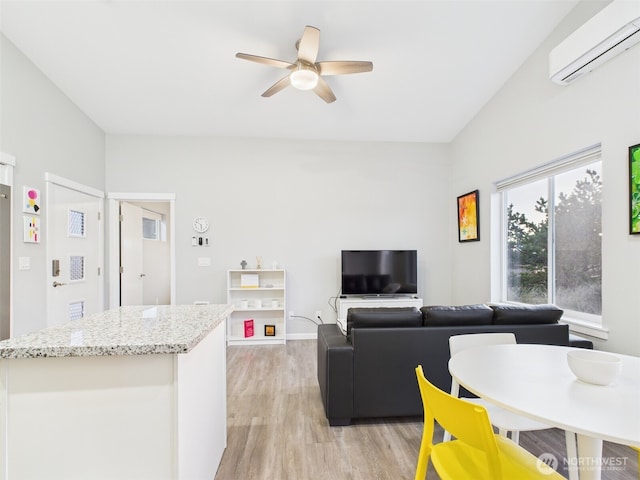 living area featuring a ceiling fan, light wood-style flooring, and a wall mounted AC