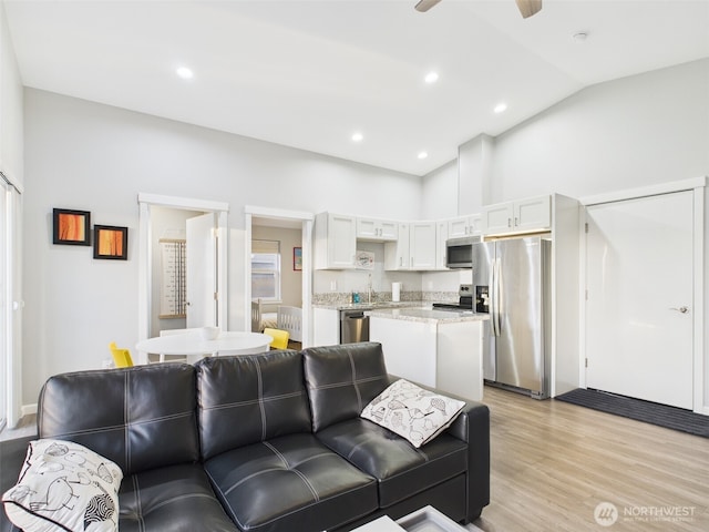 living room with light wood-type flooring, ceiling fan, lofted ceiling, and recessed lighting