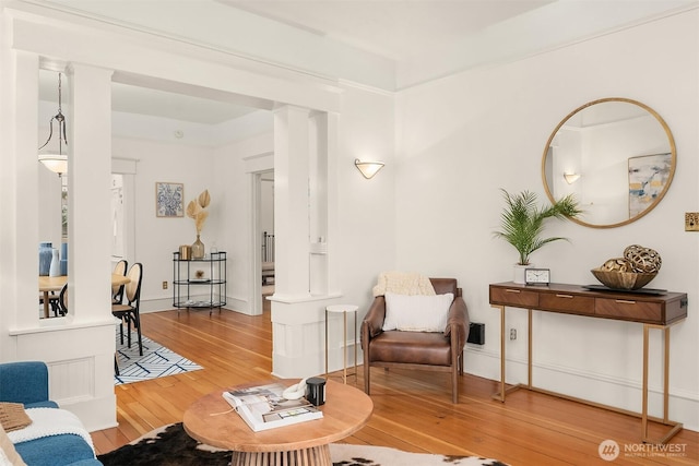 living area with hardwood / wood-style floors, baseboards, and ornate columns