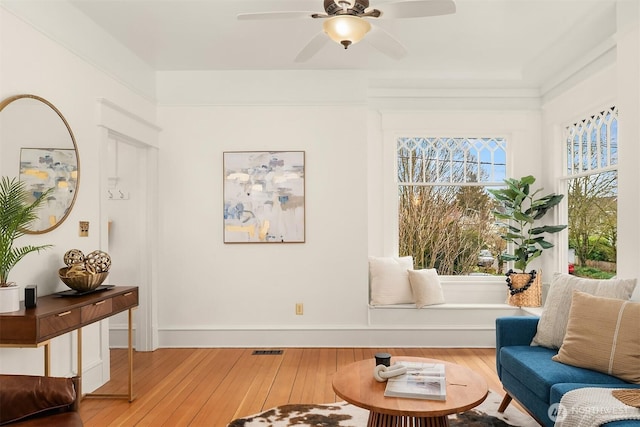 sitting room featuring hardwood / wood-style floors, baseboards, visible vents, and ceiling fan