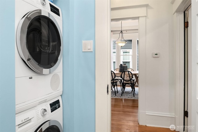 laundry room with wood finished floors, laundry area, and stacked washer / dryer