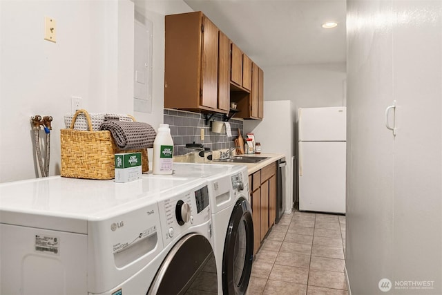 laundry room with a sink, cabinet space, washing machine and dryer, and light tile patterned flooring