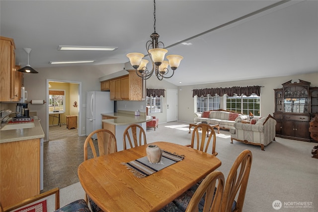 dining area with light carpet, a notable chandelier, and lofted ceiling