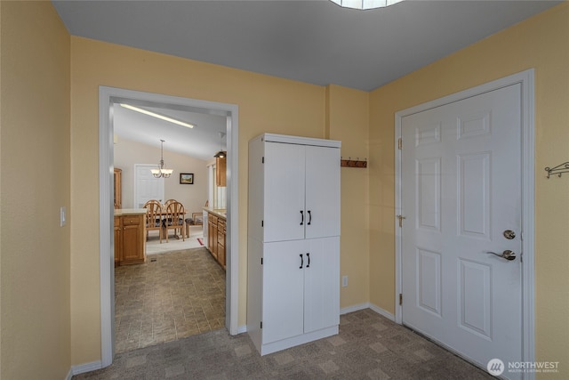 hallway featuring vaulted ceiling, carpet floors, and a chandelier