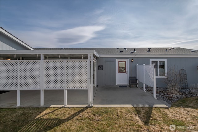 property entrance featuring a patio, a yard, and a shingled roof