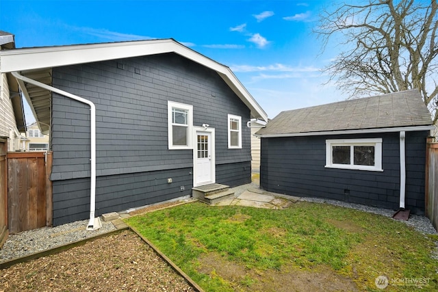 back of property with a yard, entry steps, fence, and an outdoor structure