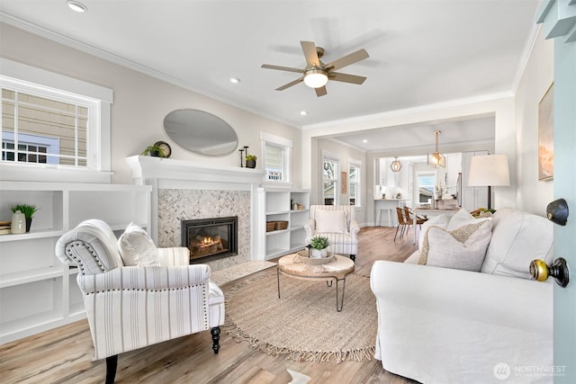 living room featuring recessed lighting, crown molding, wood finished floors, and a tile fireplace