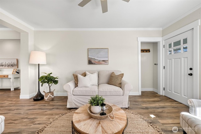 living area featuring ceiling fan, crown molding, baseboards, and wood finished floors