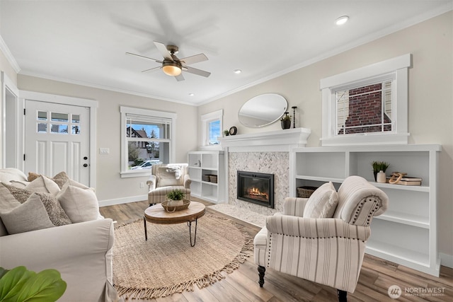 living area featuring crown molding, baseboards, a tiled fireplace, and wood finished floors