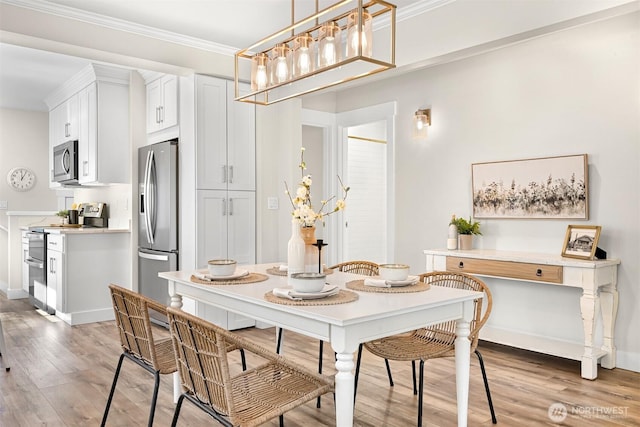 dining room featuring ornamental molding, baseboards, and light wood finished floors