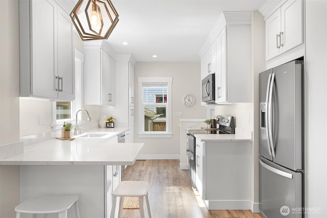 kitchen featuring appliances with stainless steel finishes, white cabinetry, a sink, and a breakfast bar area