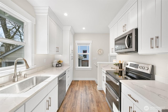 kitchen featuring stainless steel appliances, a sink, white cabinetry, and light wood-style floors