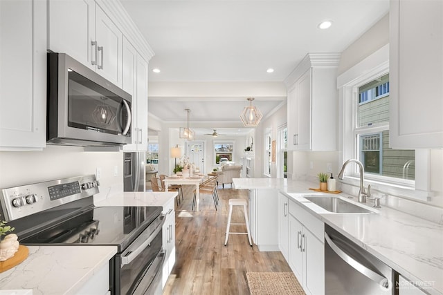 kitchen featuring stainless steel appliances, white cabinetry, a sink, and light wood-style flooring