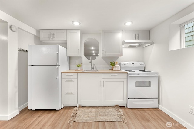 kitchen with white appliances, a sink, light wood-style flooring, and under cabinet range hood