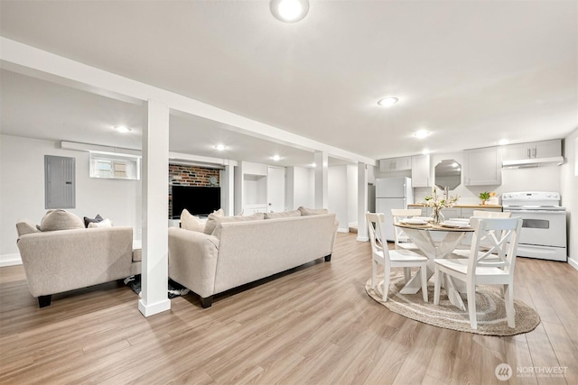 living area with light wood-style floors, electric panel, baseboards, and recessed lighting