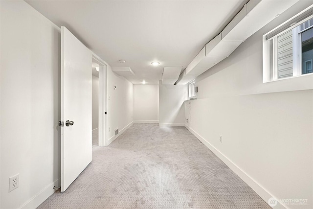 finished below grade area featuring light colored carpet, visible vents, and baseboards