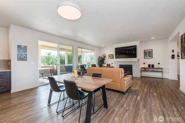 dining room featuring a fireplace, recessed lighting, dark wood-style floors, and baseboards