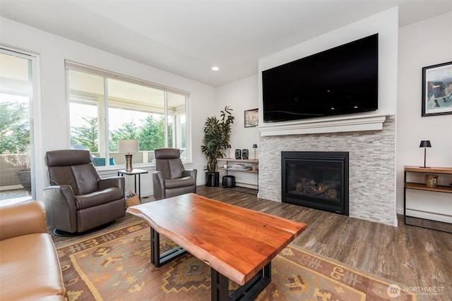 living room with a stone fireplace, recessed lighting, and wood finished floors