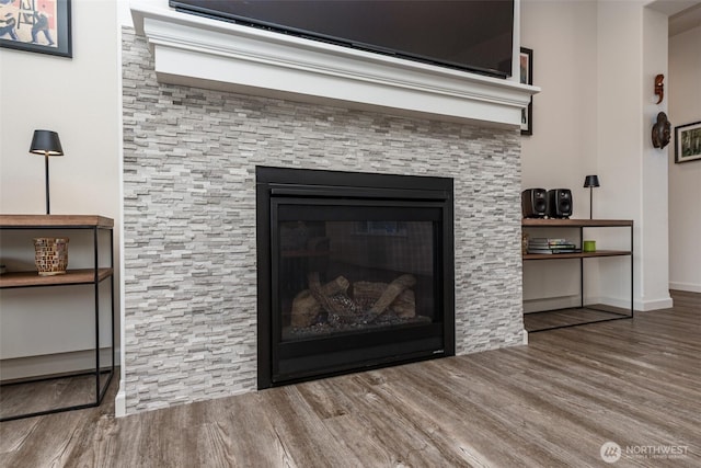 room details with baseboards, wood finished floors, and a glass covered fireplace