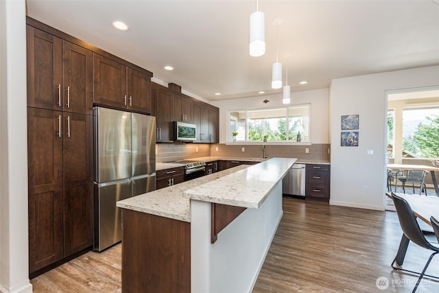 kitchen with a center island, backsplash, stainless steel appliances, and wood finished floors