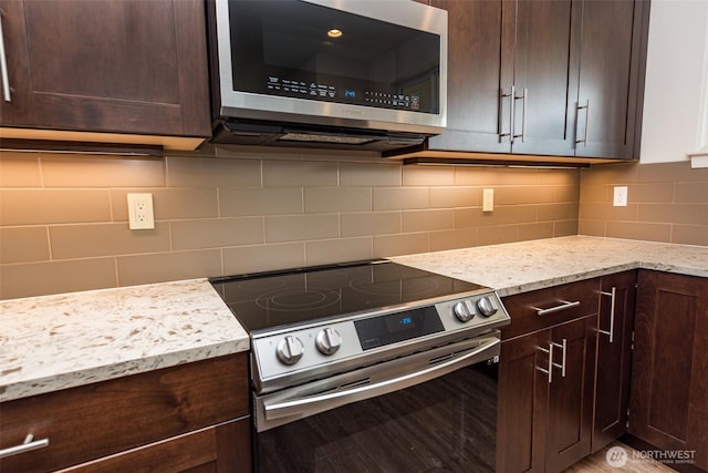 kitchen featuring light stone counters, dark brown cabinetry, and appliances with stainless steel finishes