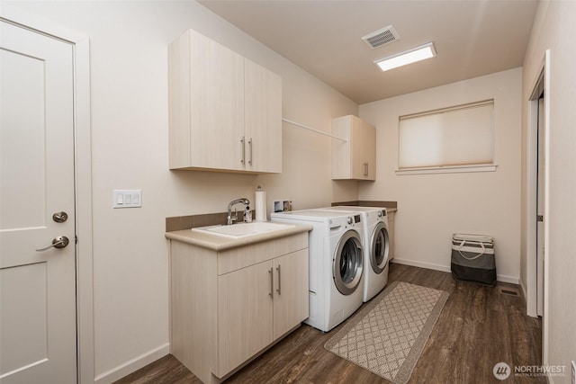 clothes washing area with visible vents, cabinet space, separate washer and dryer, a sink, and dark wood-type flooring