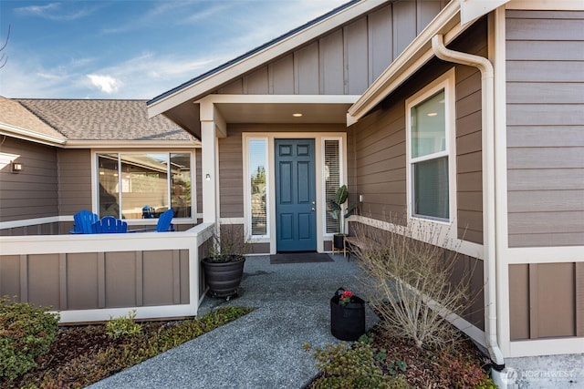 view of exterior entry with board and batten siding and roof with shingles