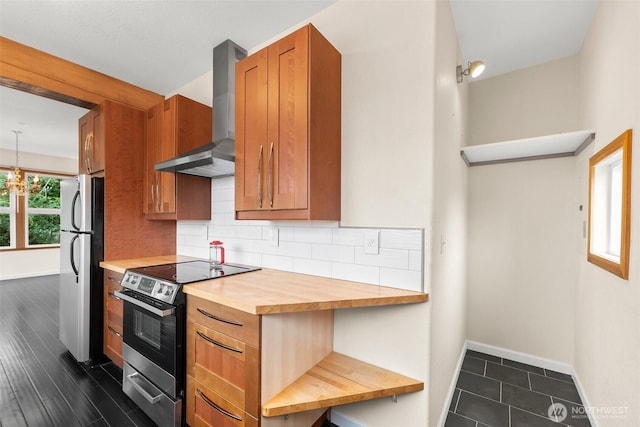 kitchen featuring baseboards, stainless steel appliances, decorative backsplash, wood counters, and wall chimney exhaust hood