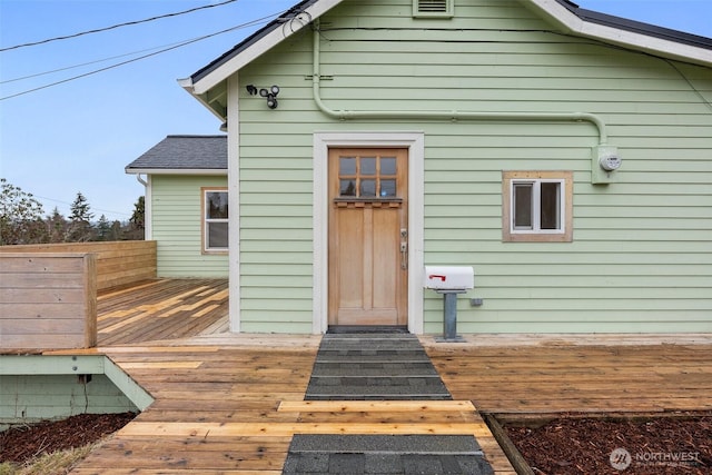 back of house with a deck, fence, and roof with shingles