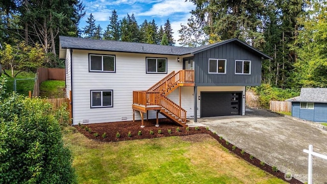 view of front of house with concrete driveway, an attached garage, stairs, fence, and board and batten siding