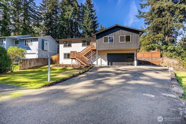 view of front of home featuring a garage, fence, driveway, and stairs