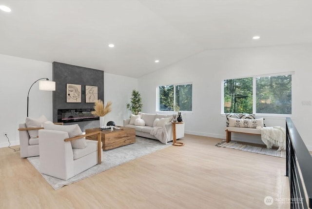 living room featuring light wood finished floors, baseboards, lofted ceiling, a fireplace, and recessed lighting