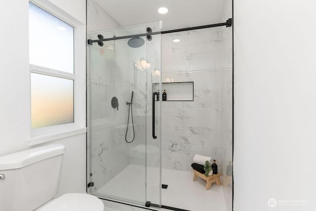 bathroom with toilet and a marble finish shower