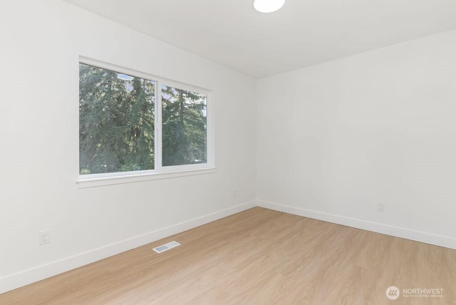 unfurnished room featuring visible vents, light wood-style flooring, and baseboards