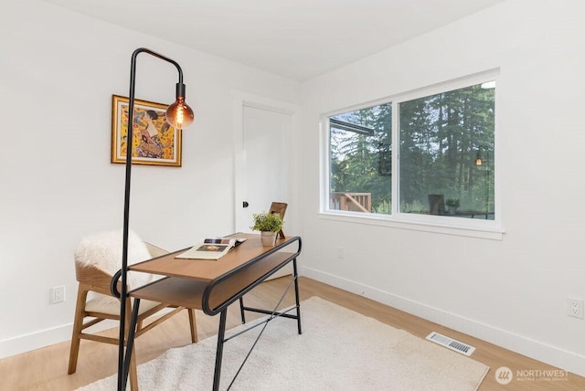 home office with light wood-style flooring, visible vents, and baseboards