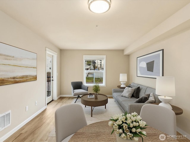 living room with baseboards, visible vents, and light wood finished floors