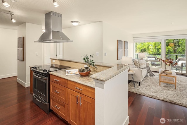 kitchen with light stone counters, exhaust hood, brown cabinets, stainless steel electric range oven, and dark wood finished floors