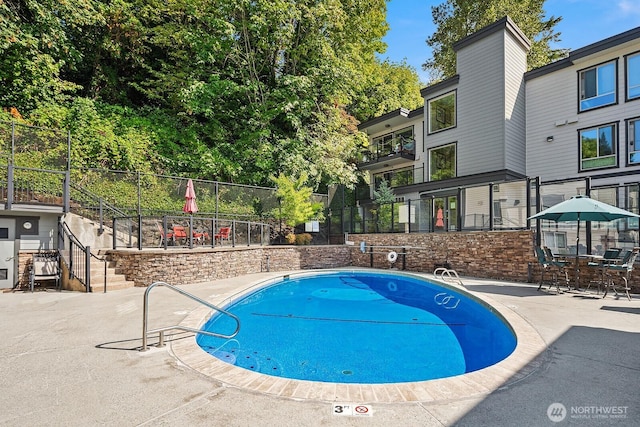 community pool featuring fence and a patio